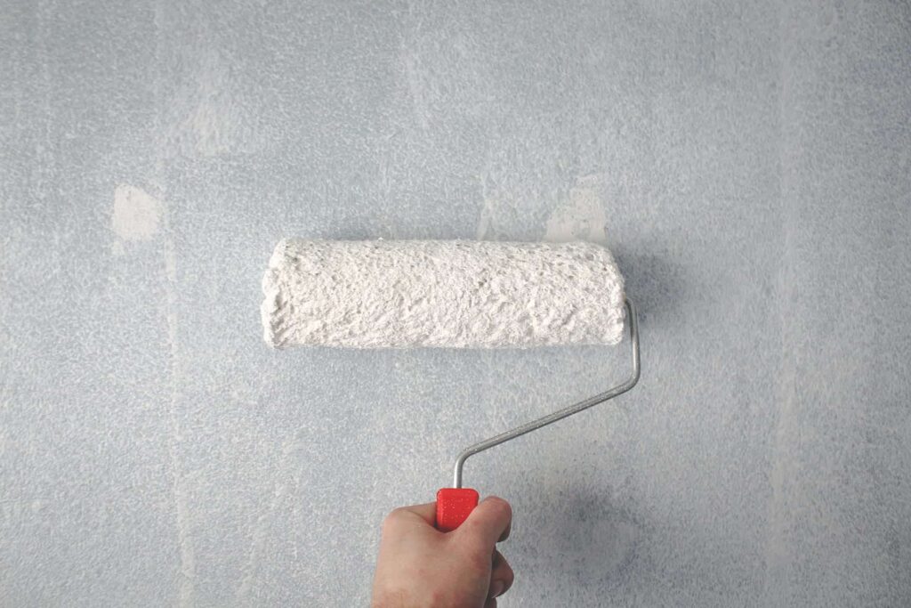 Rolling fresh paint onto a wall during a rental turnover