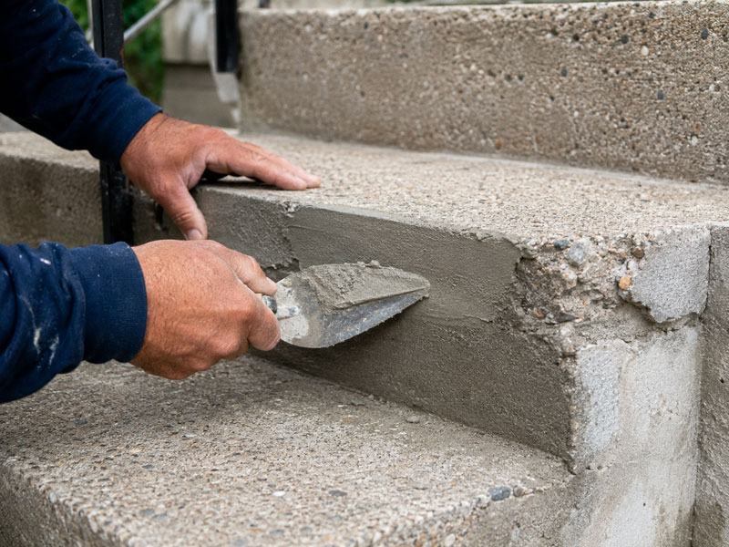 Smoothing fresh concrete on a set of steps with a trowel
